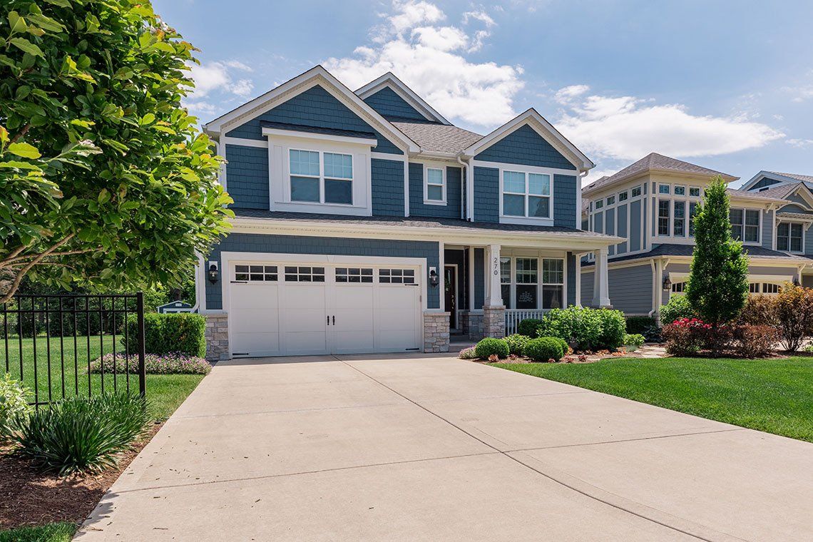 A large blue and white house with a white garage door is for sale.