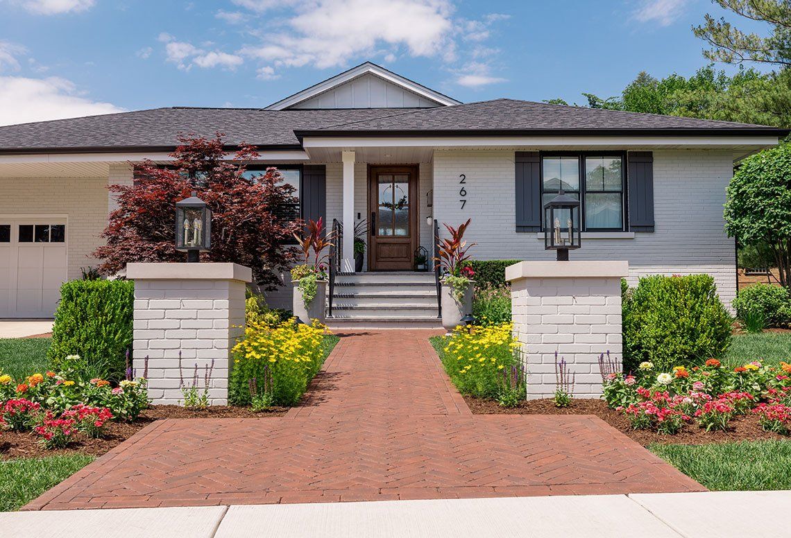 A white house with a brick walkway leading to the front door.
