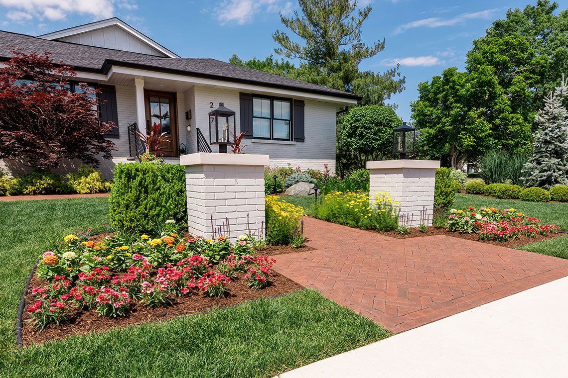 A white house with a lush green lawn and flowers in front of it.