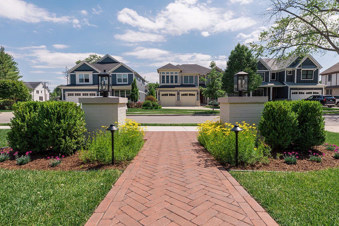 A brick walkway leading to a row of houses in a residential neighborhood.