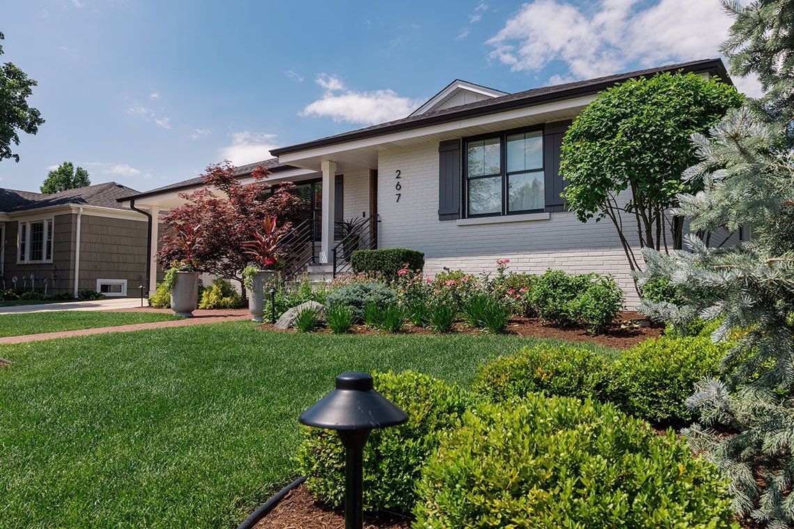 A house with a lush green lawn and bushes in front of it.