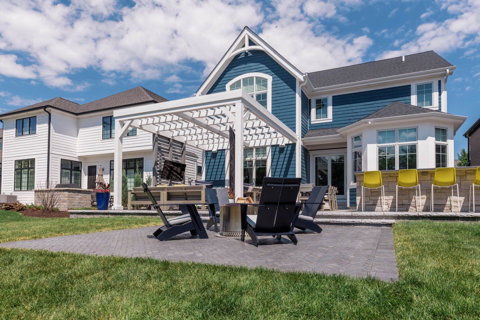 A large house with a pergola and chairs in front of it.