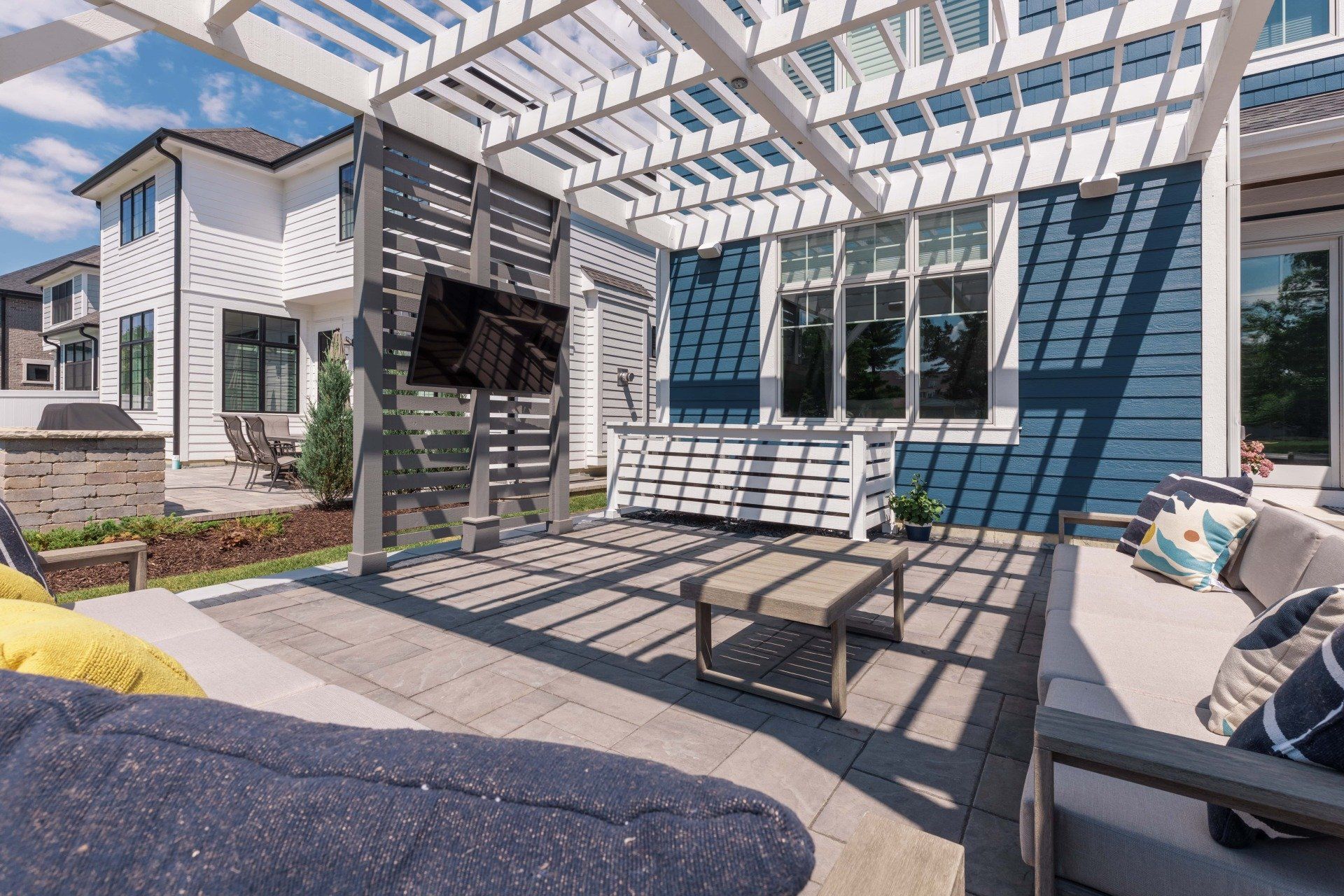 An artist 's impression of a backyard with a pergola and patio furniture.