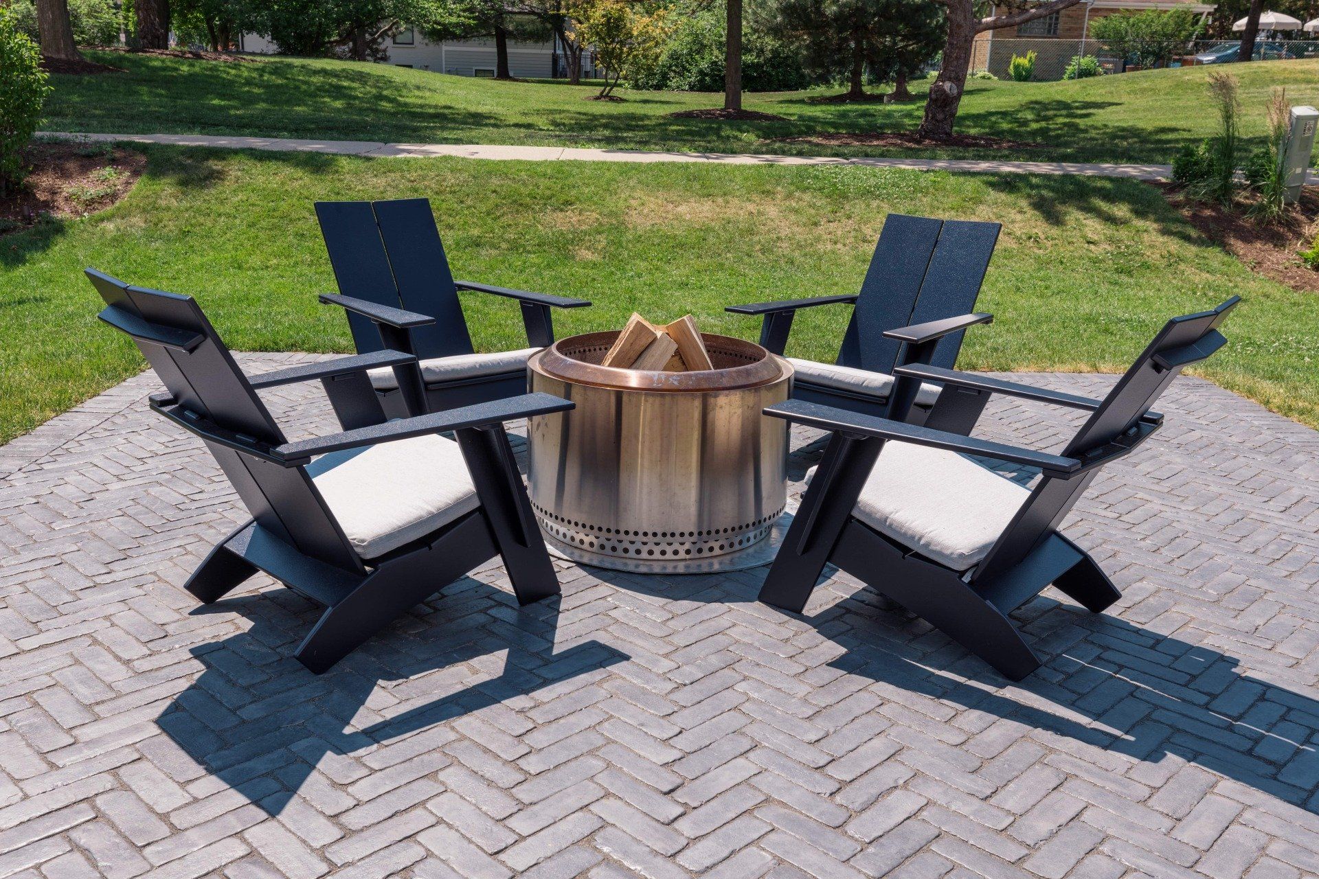 Four chairs are sitting around a fire pit on a patio.
