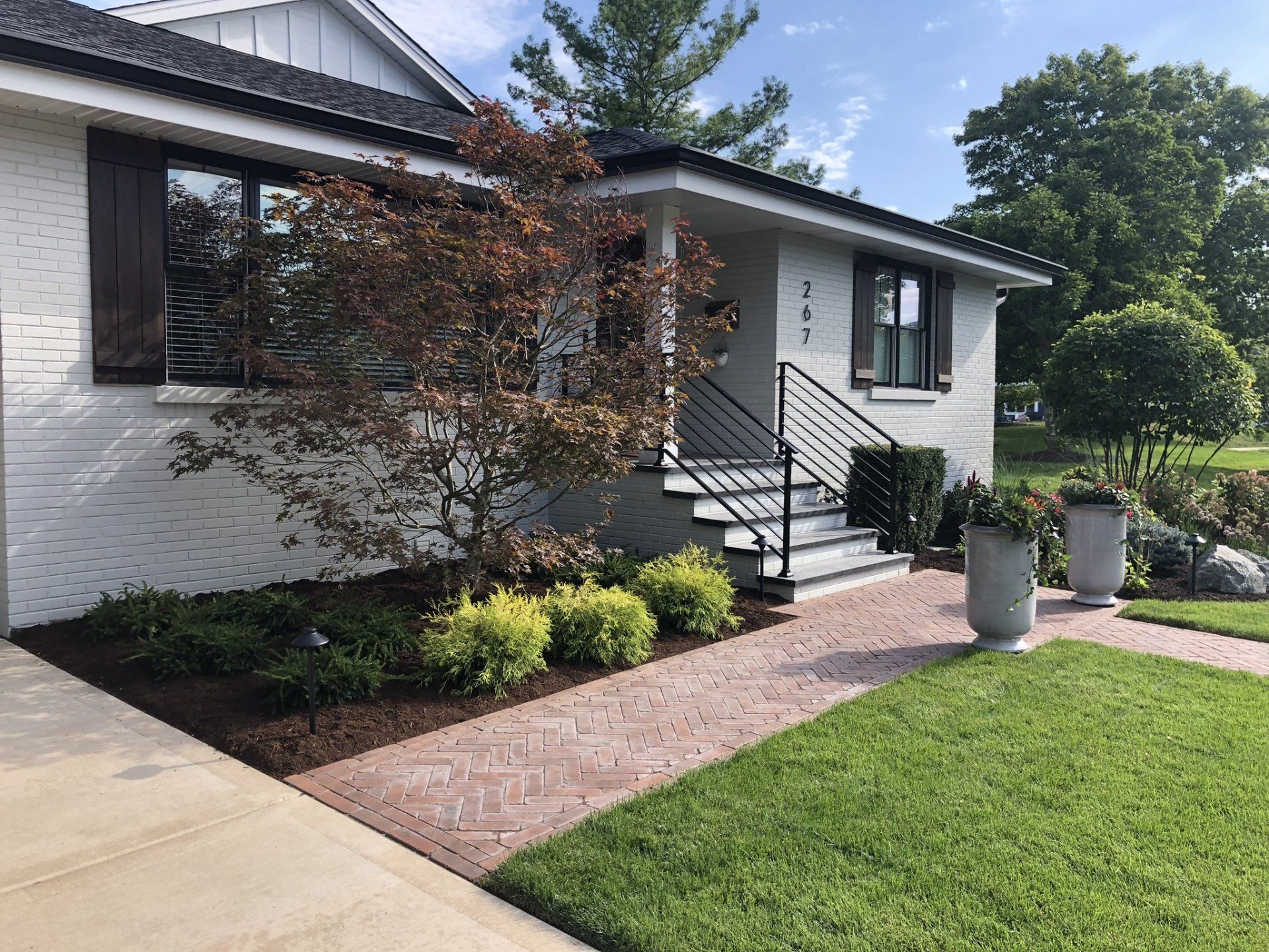 A white brick house with a brick walkway leading to the front door.