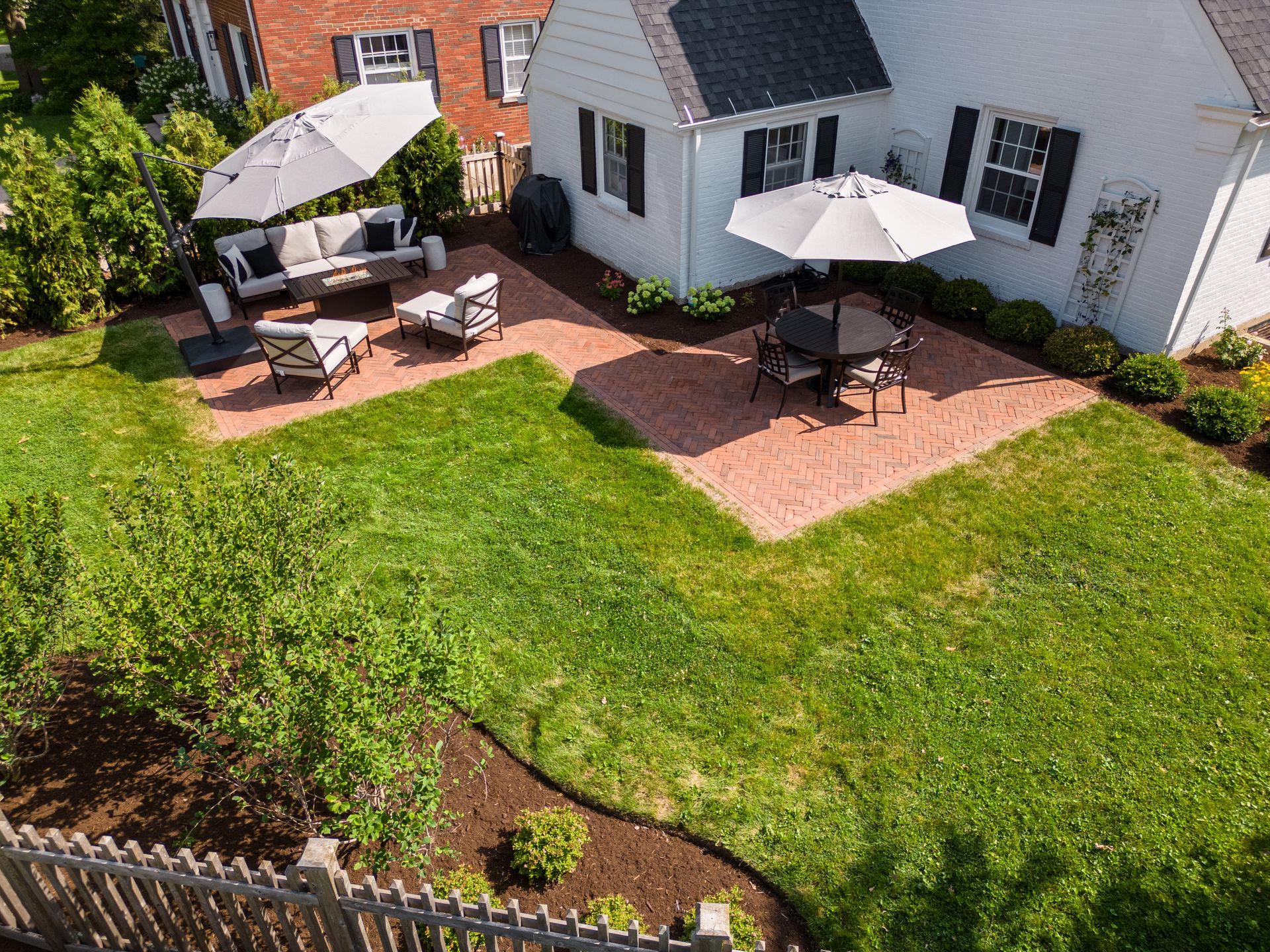 An aerial view of a backyard with patio furniture and umbrellas.