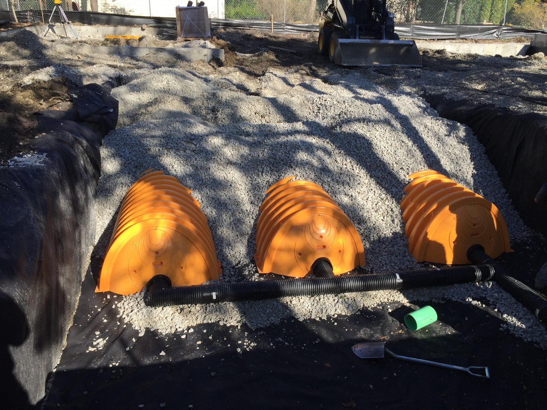 Three orange containers are sitting on top of a pile of gravel.