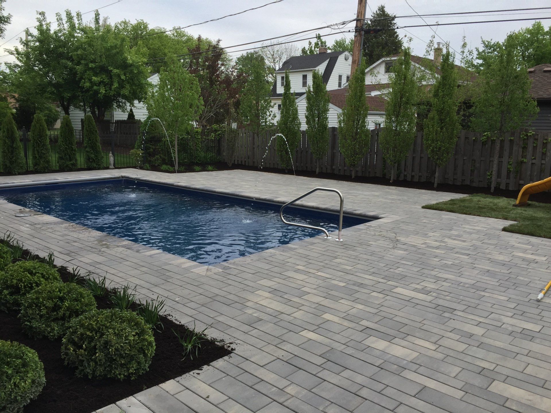A large swimming pool is in the backyard of a house.