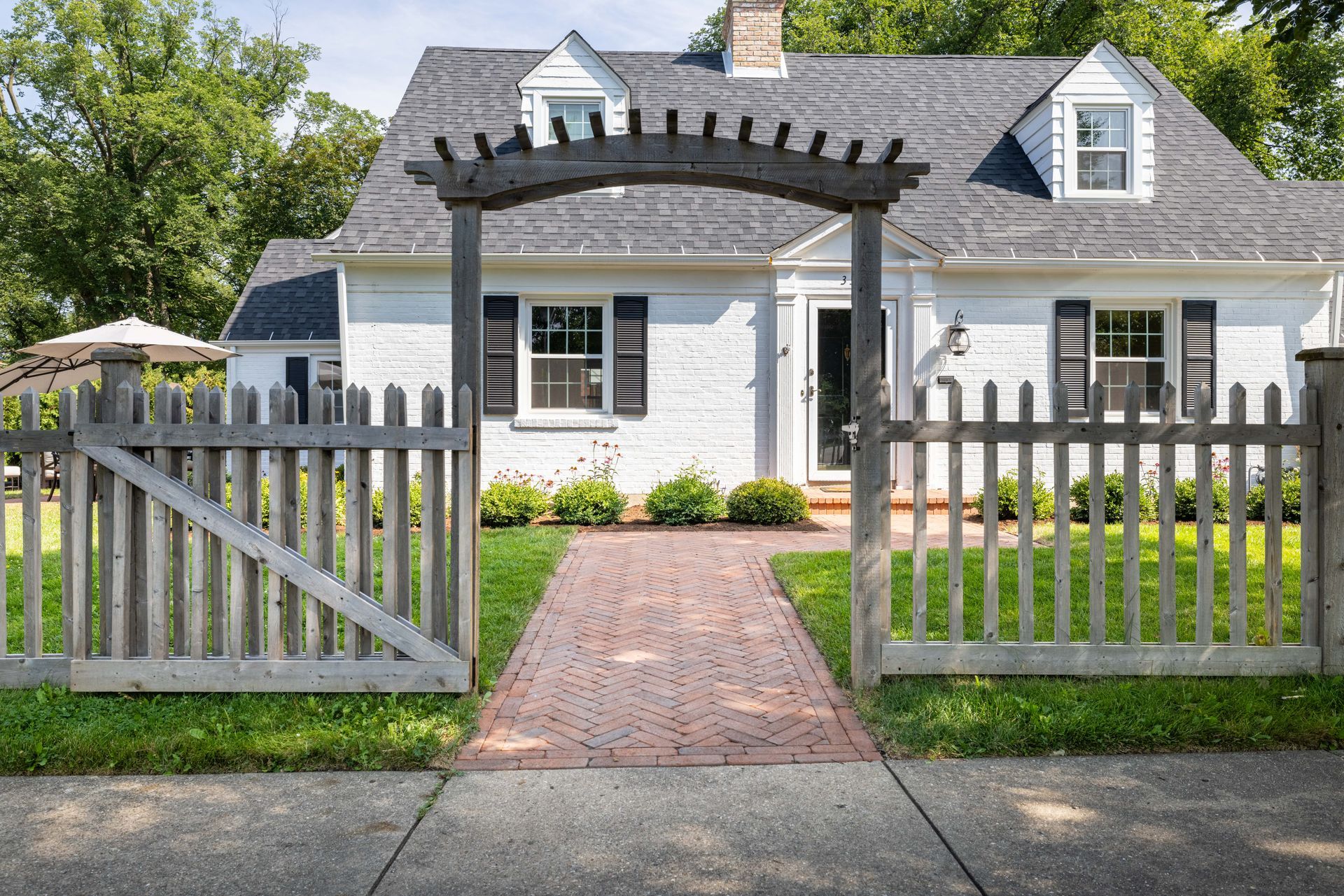 A white house with a wooden picket fence in front of it.