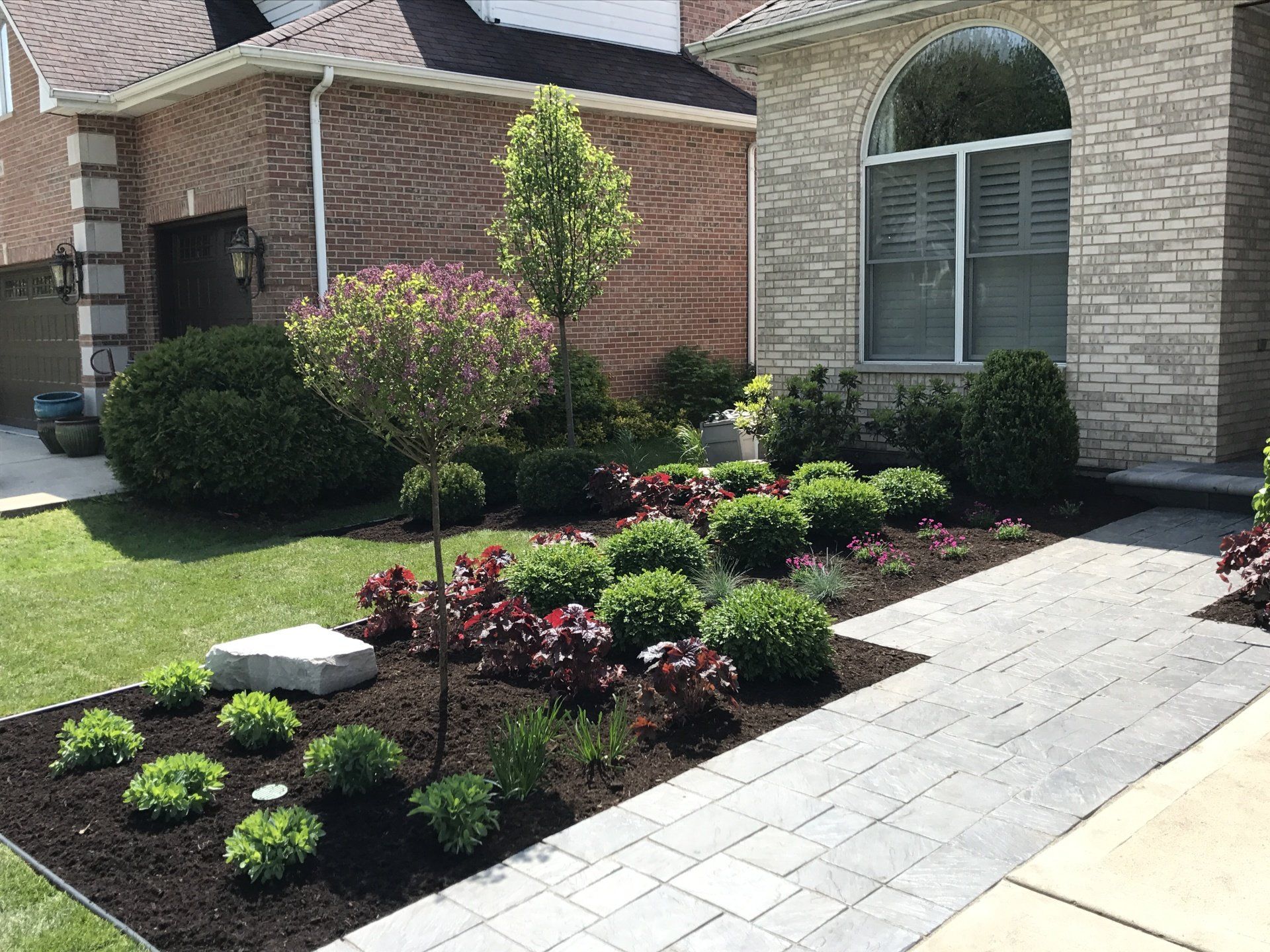 A brick house with a lush green lawn and a walkway in front of it.