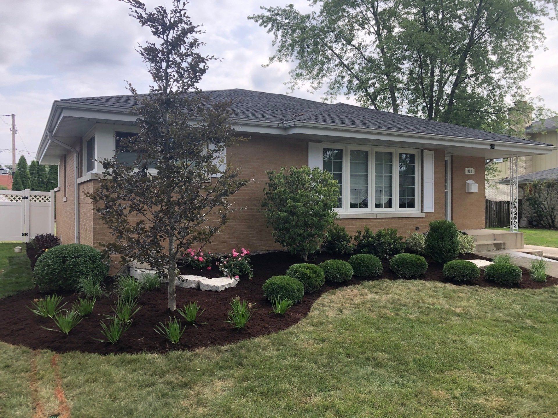 A brick house with a lush green lawn in front of it.