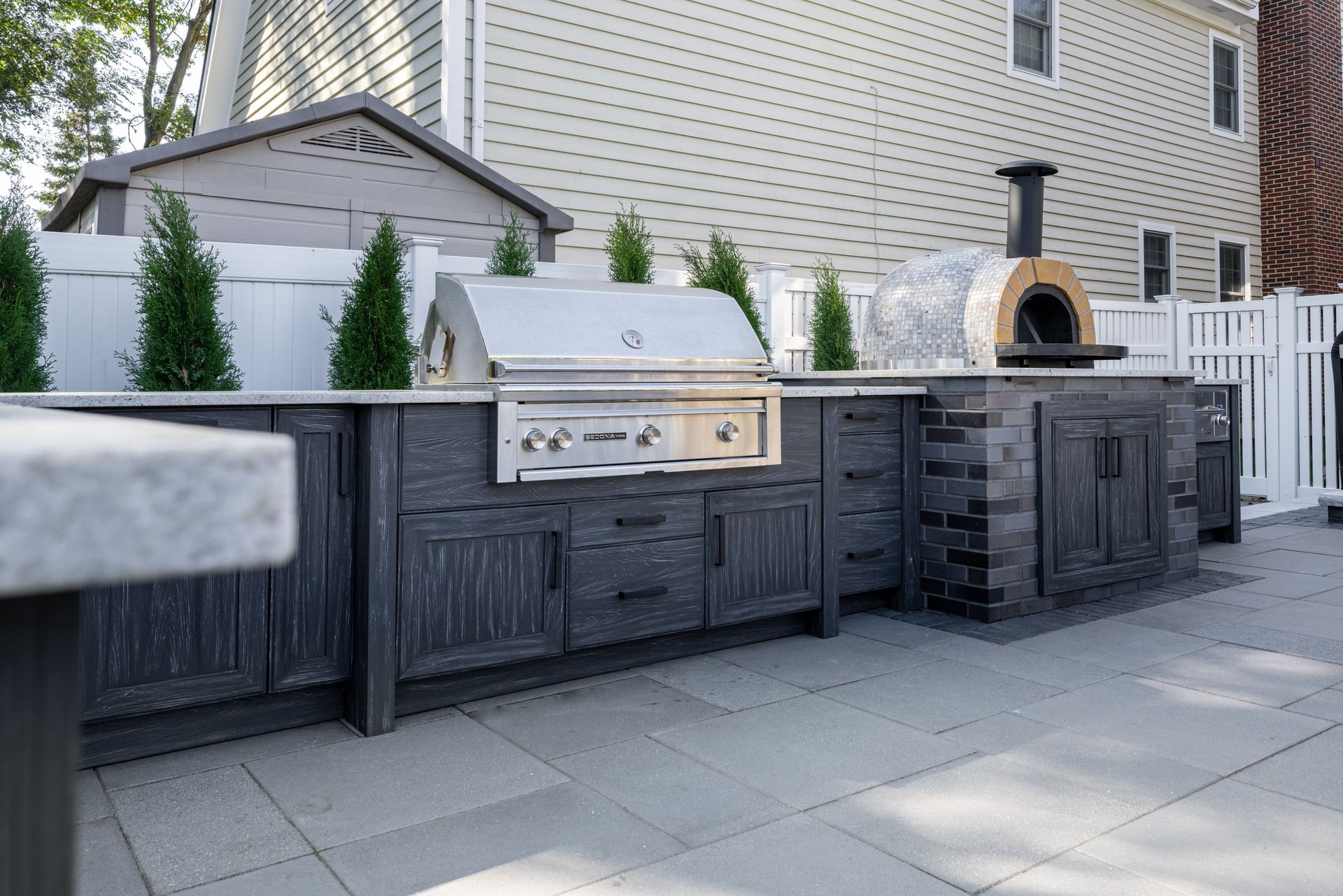 A large outdoor kitchen with a grill and a pizza oven.