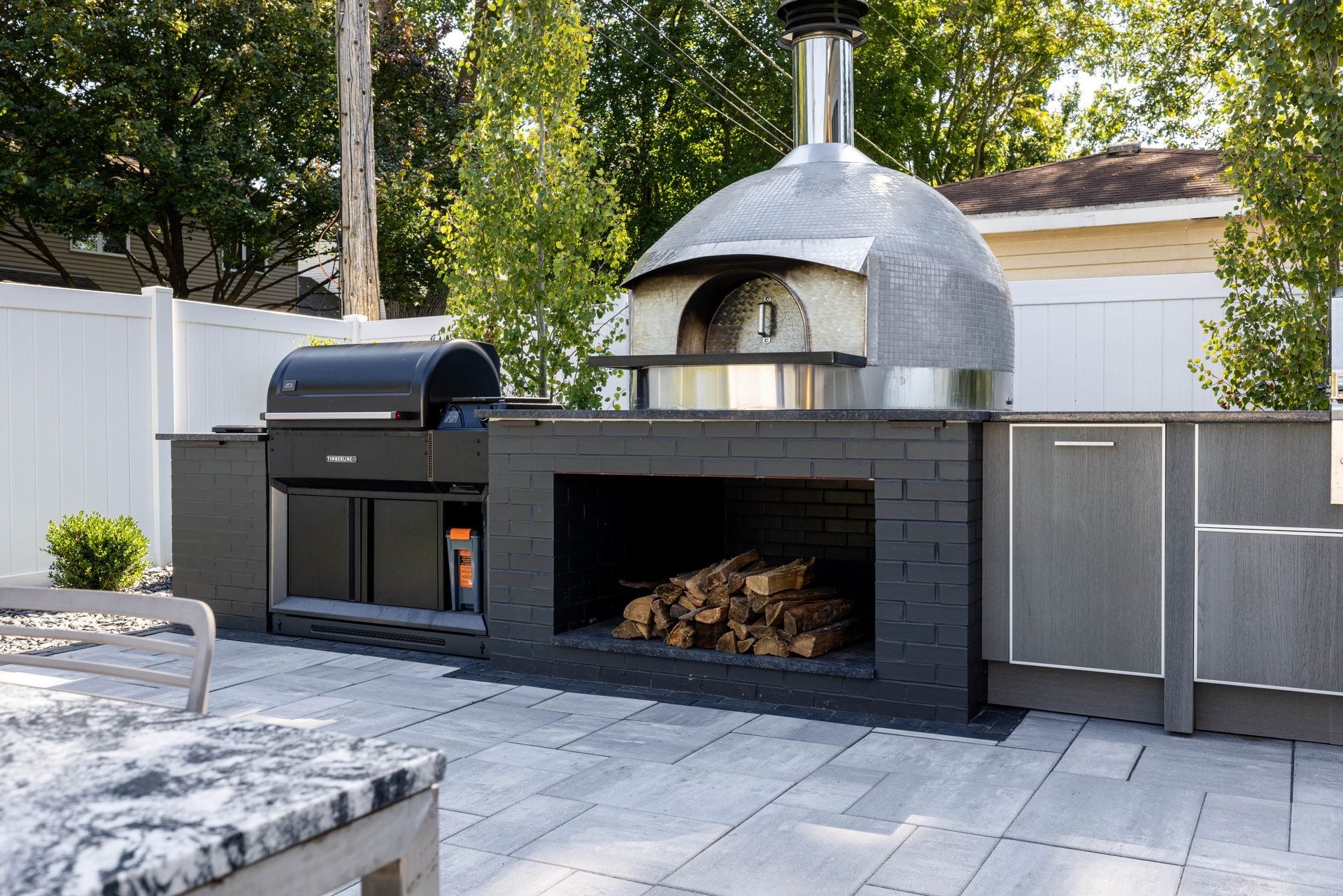 An outdoor kitchen with a pizza oven and a grill.