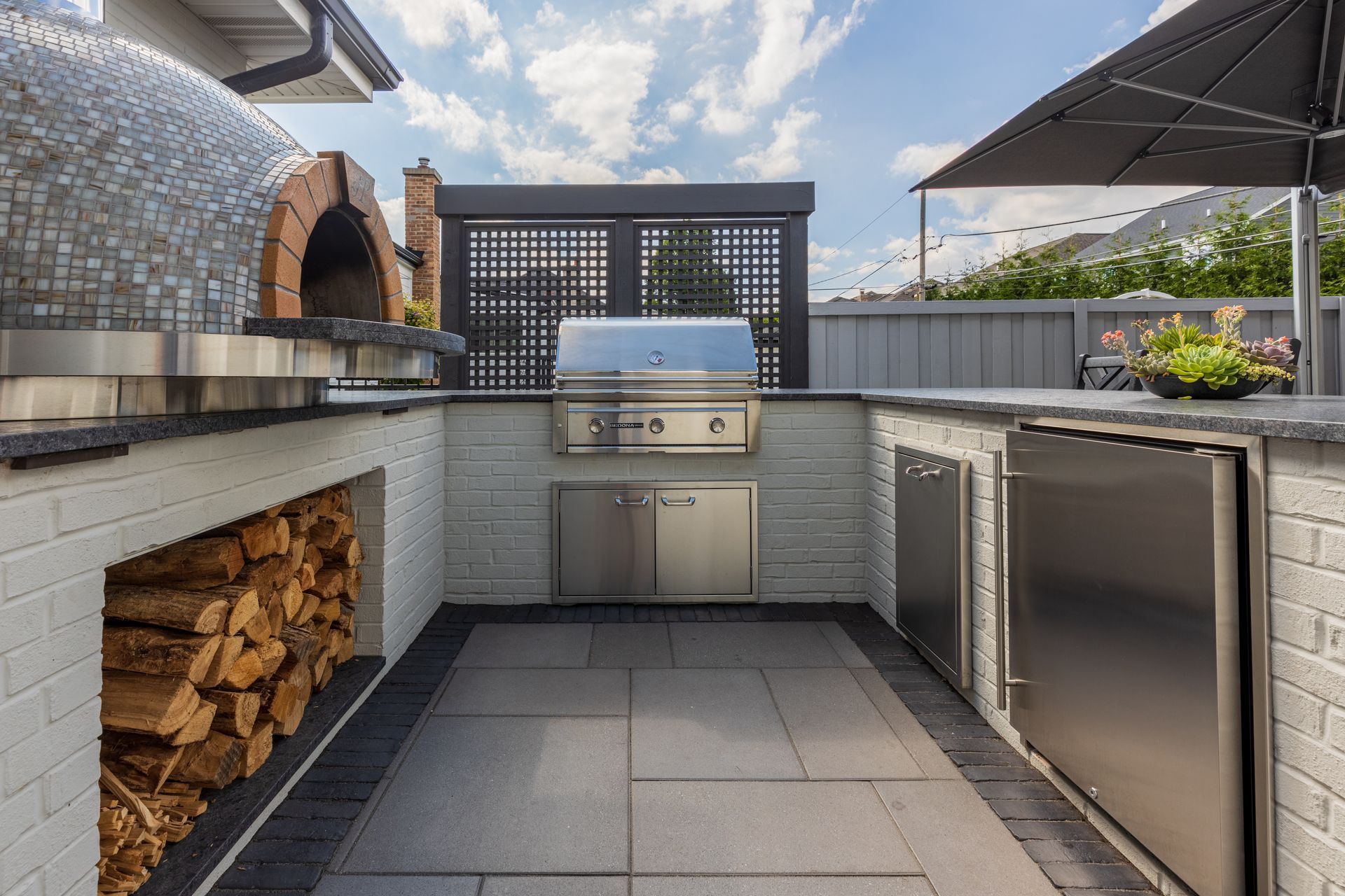 A large outdoor kitchen with a grill and a wood oven.
