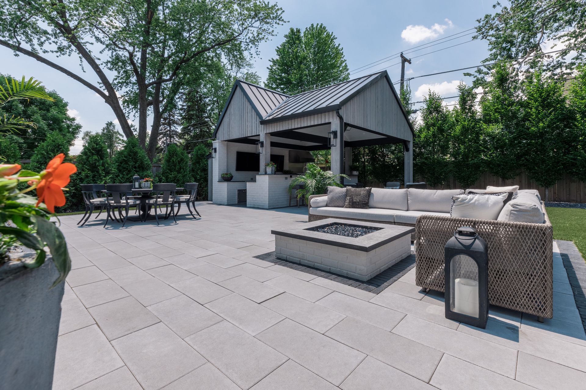 A patio with a fire pit , couch , table and chairs.