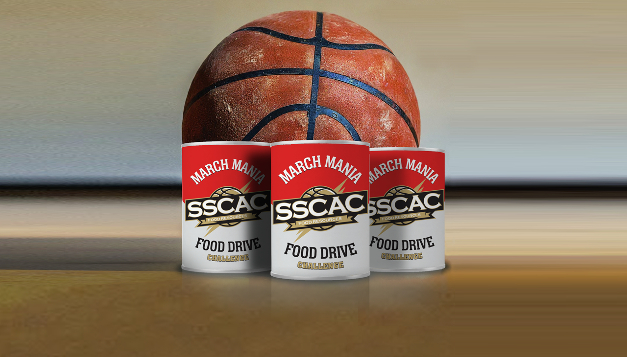 Three cans of food with food drive labels in front of a basketball.