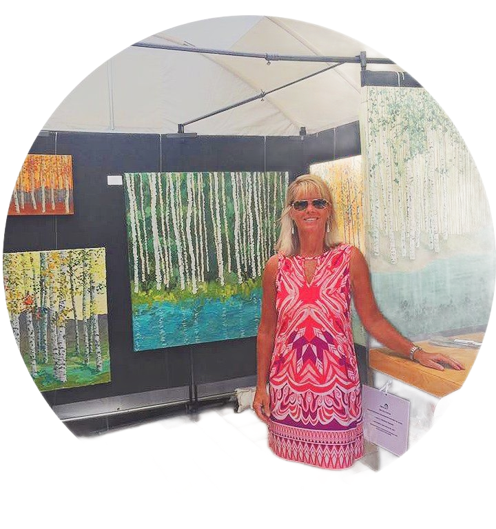 Woman in colorful dress at art gallery, standing by abstract paintings of trees.