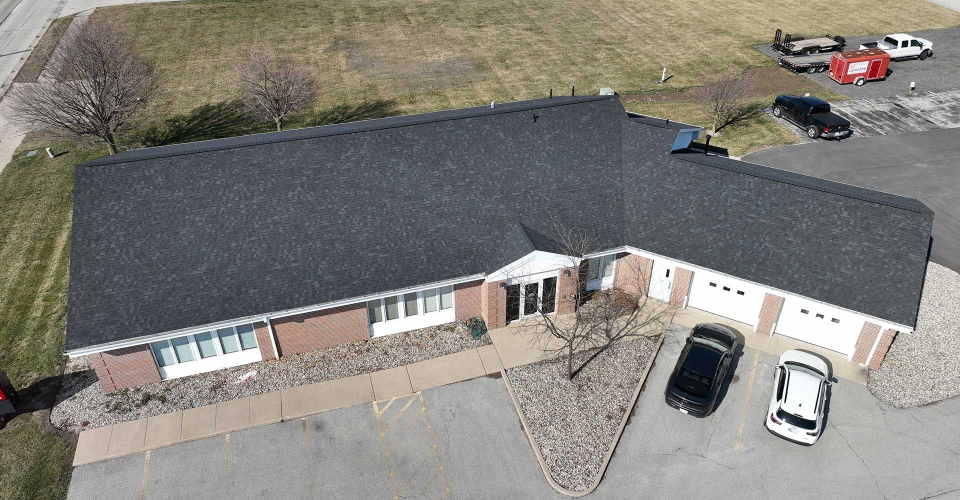 An aerial view of a house with cars parked in front of it.