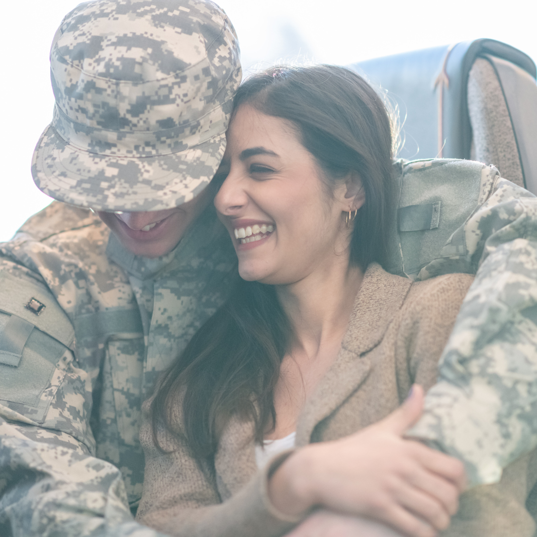 A man in a military uniform is hugging a woman