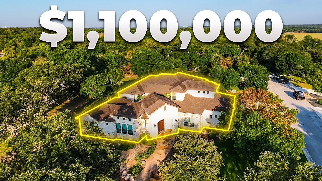Aerial view of a large house surrounded by trees, with a $1,100,000 price overlay.