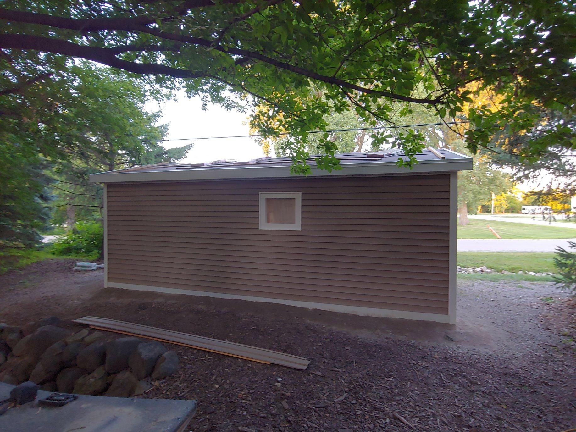 A shed with a square window on the side of it