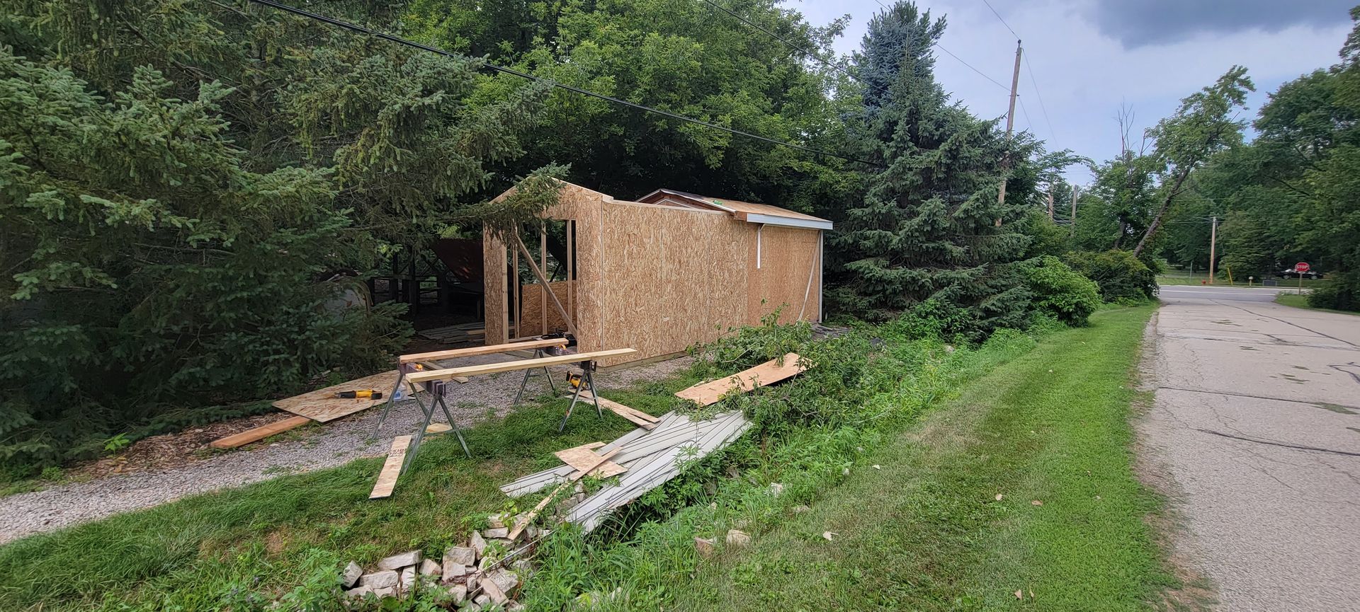 A small wooden shed is sitting on the side of a road.