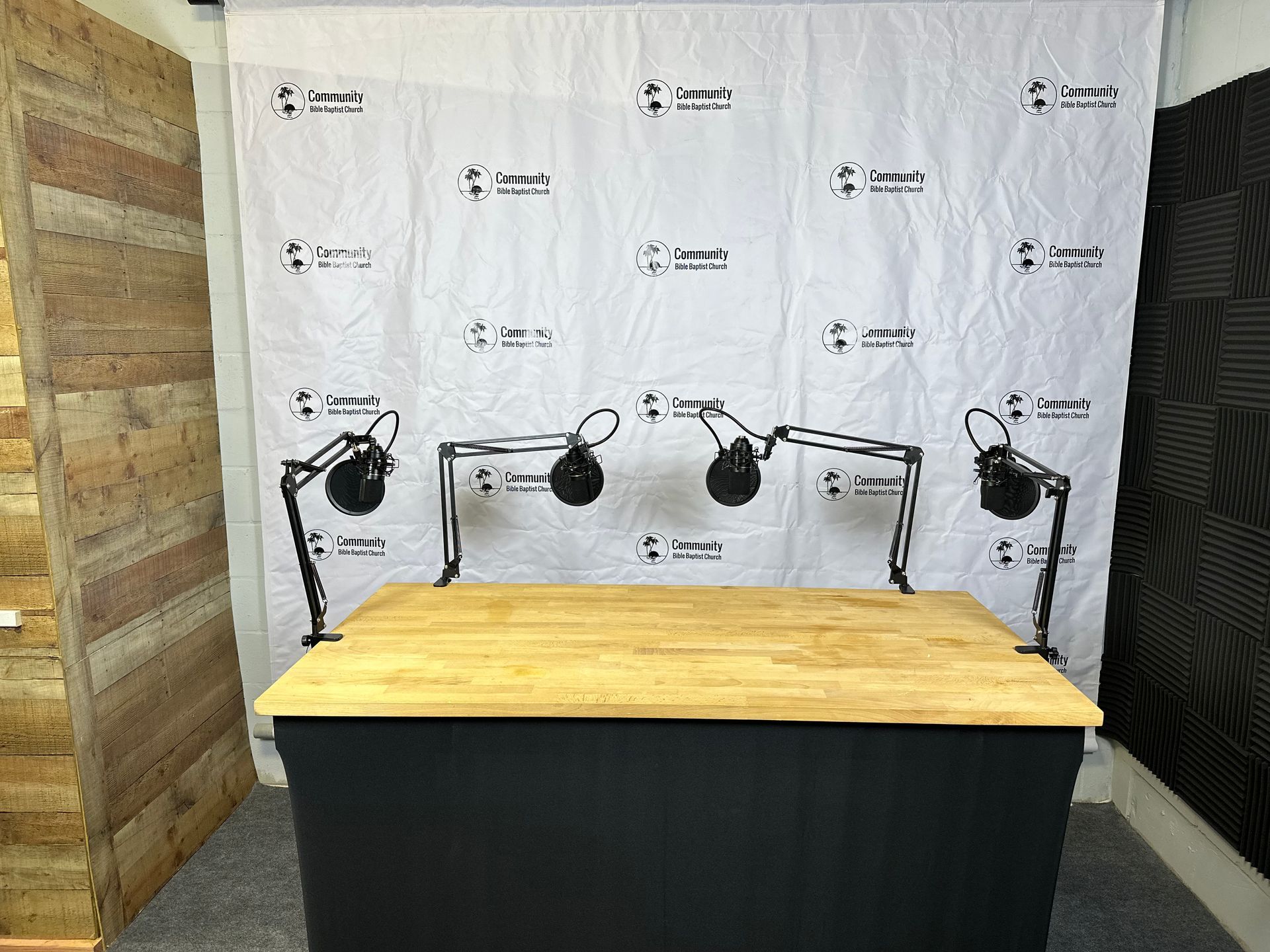 A wooden table with three microphones on it in a room.