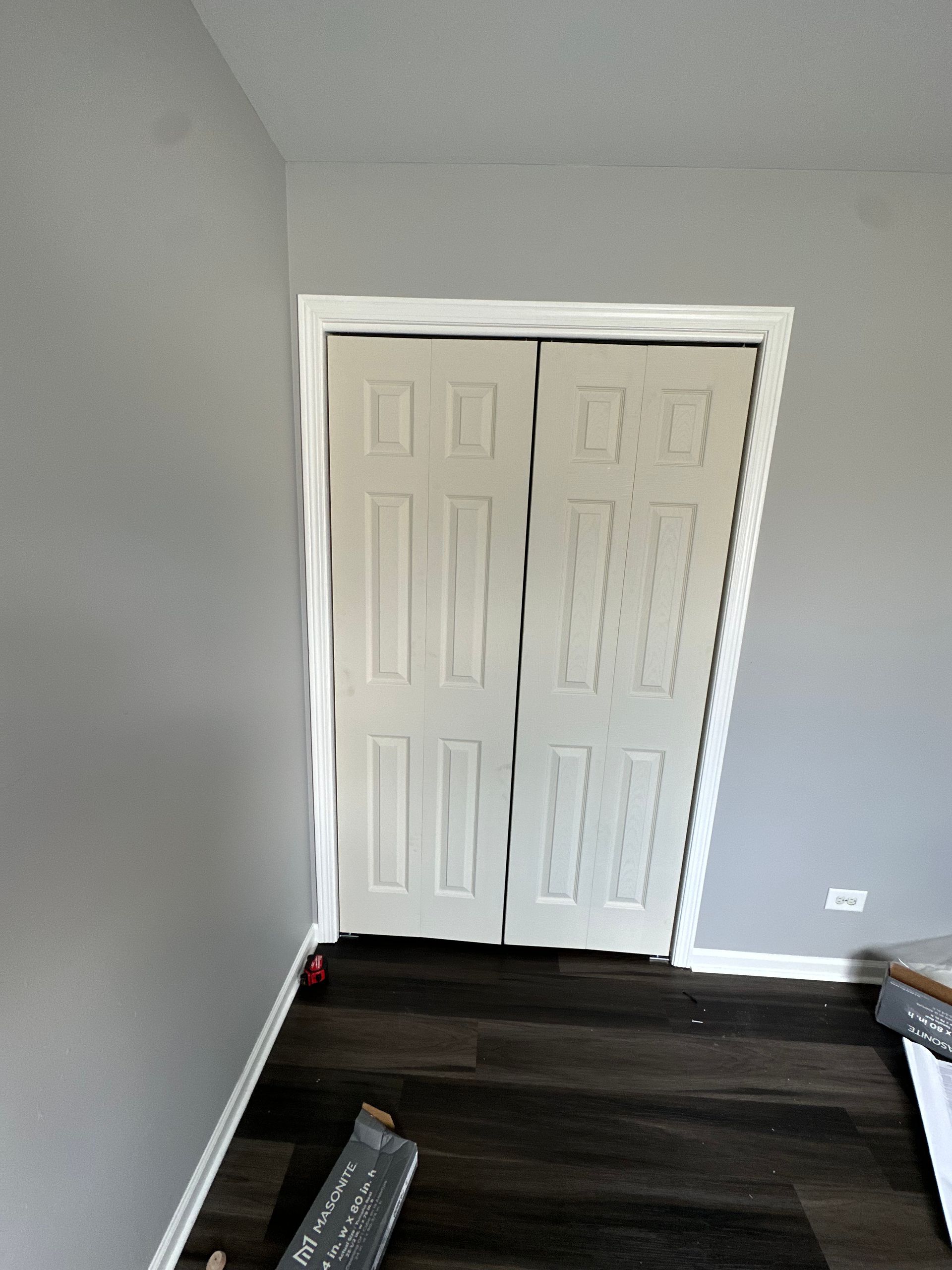 A room with a closet door and a wooden floor.