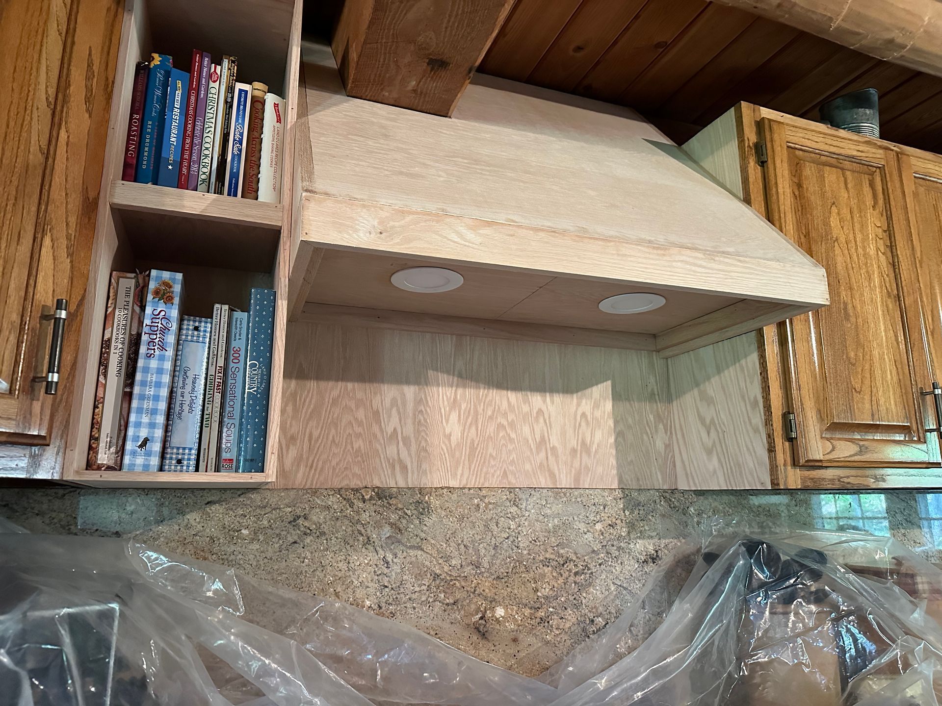 A kitchen with wooden cabinets and a hood with books on it
