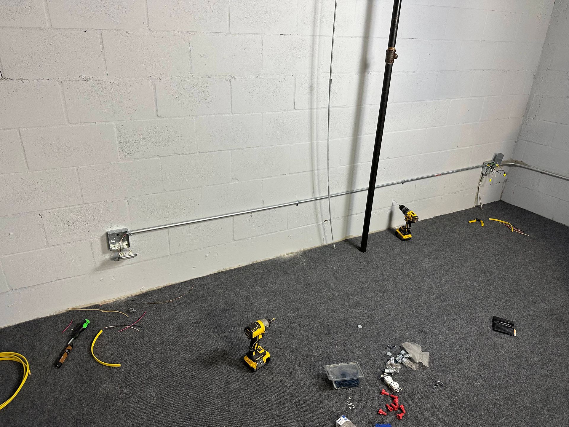 A basement with electrical conduit installed along the cinder block walls