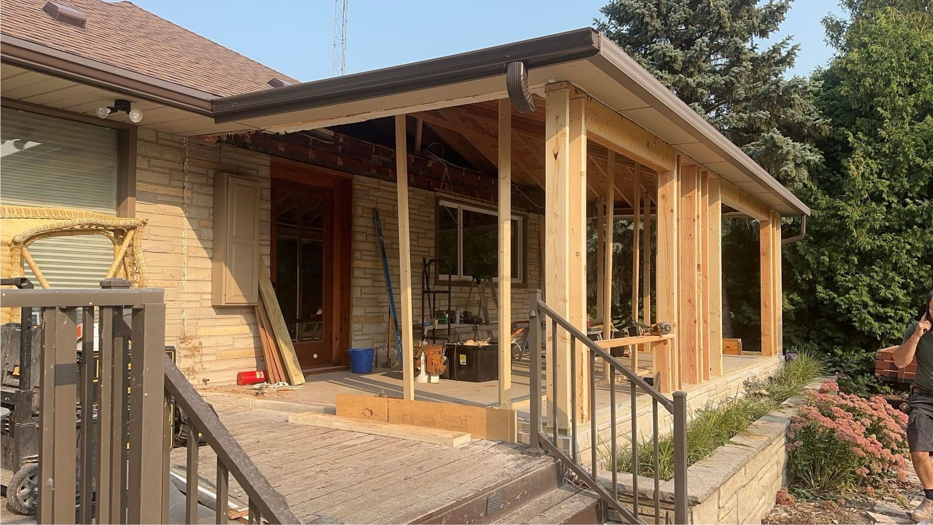 A man is standing in front of a house that is being remodeled.
