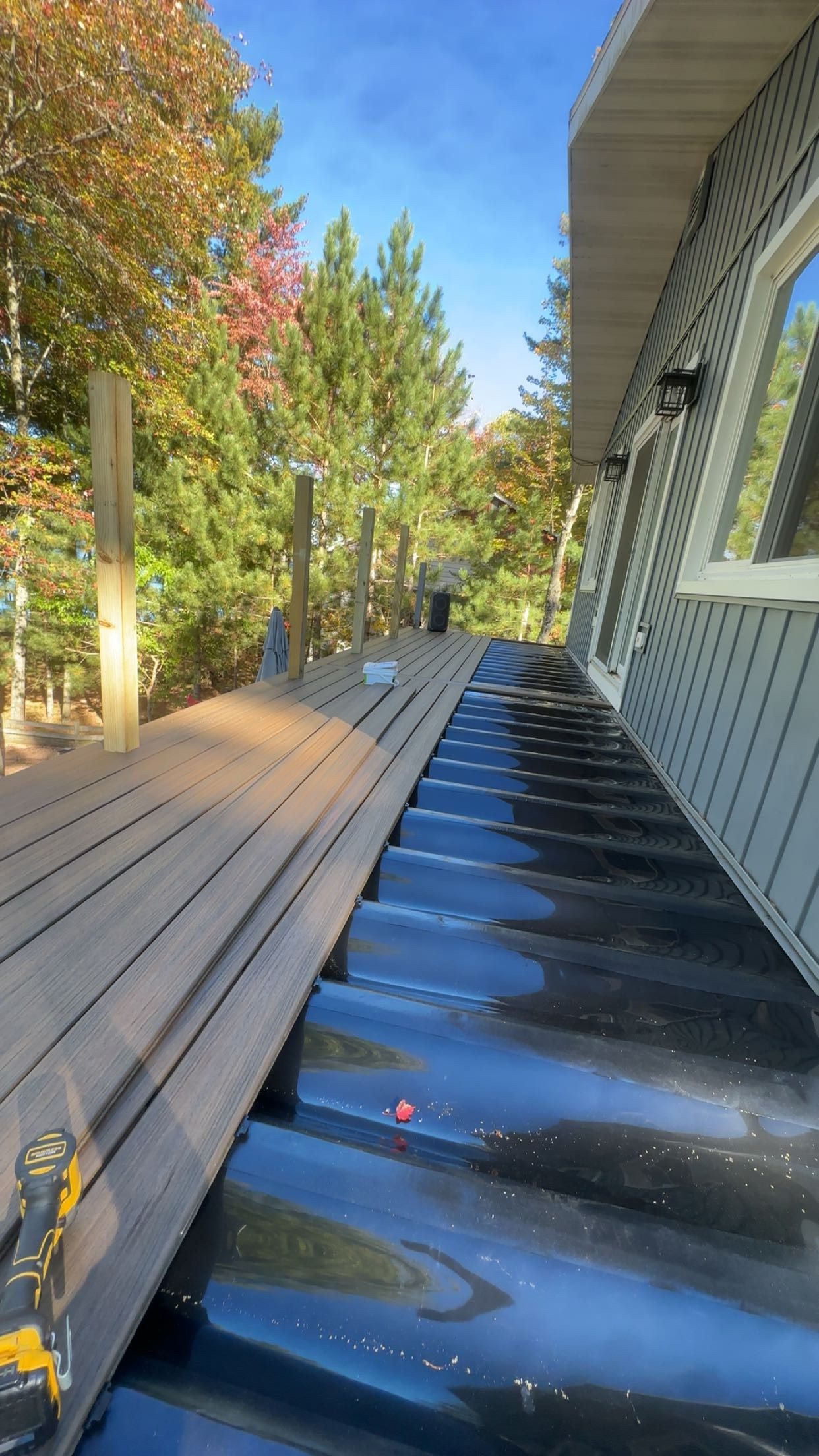 A wooden deck is being painted black in front of a house.