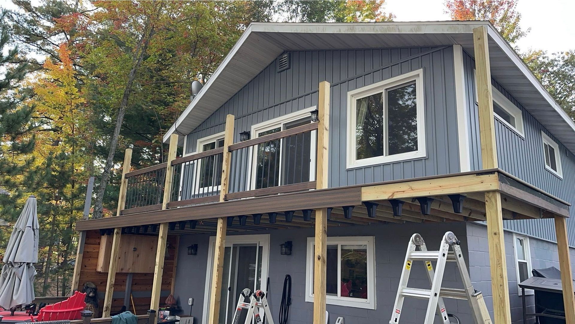 A house with a large deck and a ladder in front of it.