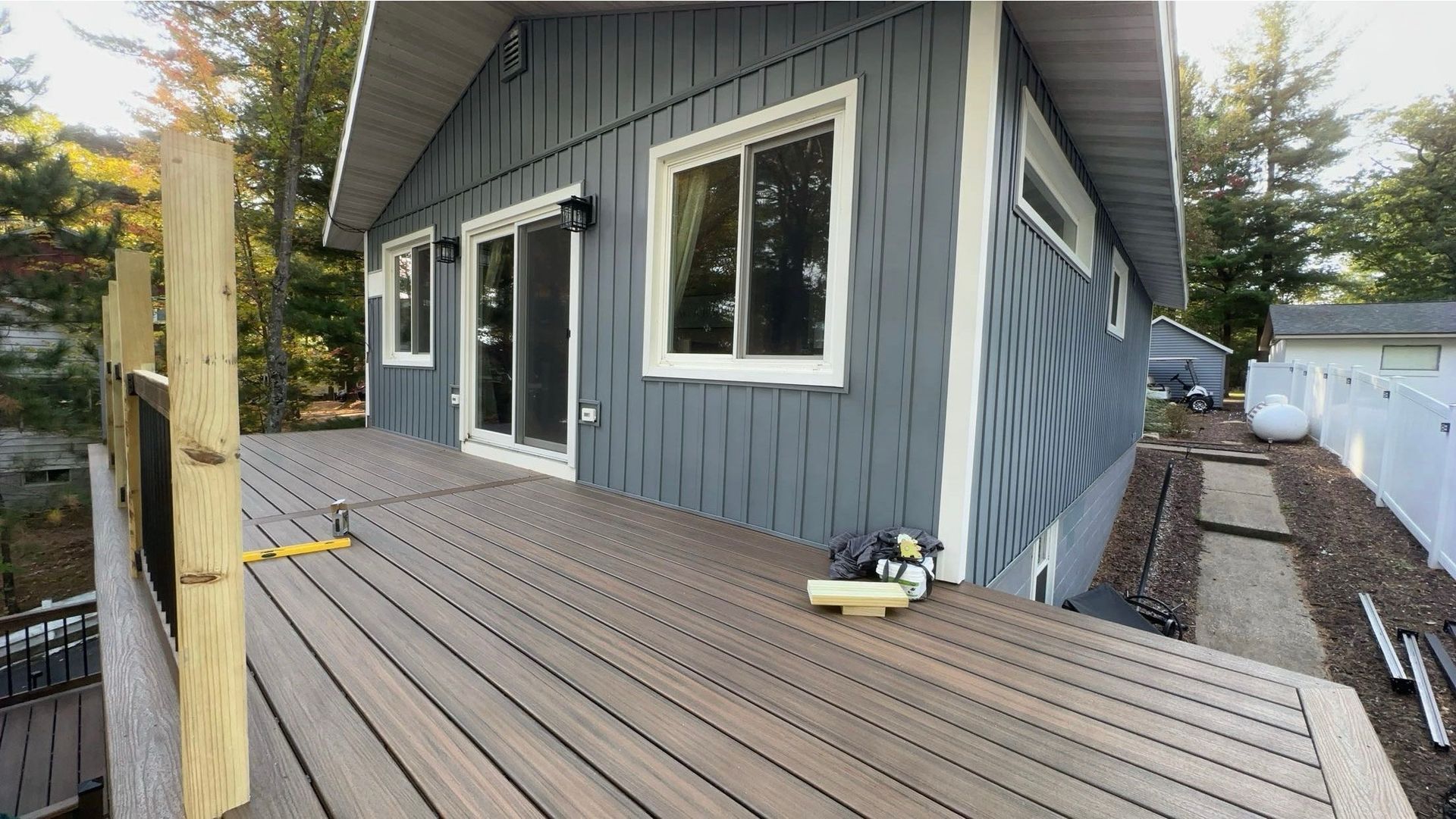 A blue house with a wooden deck in front of it.