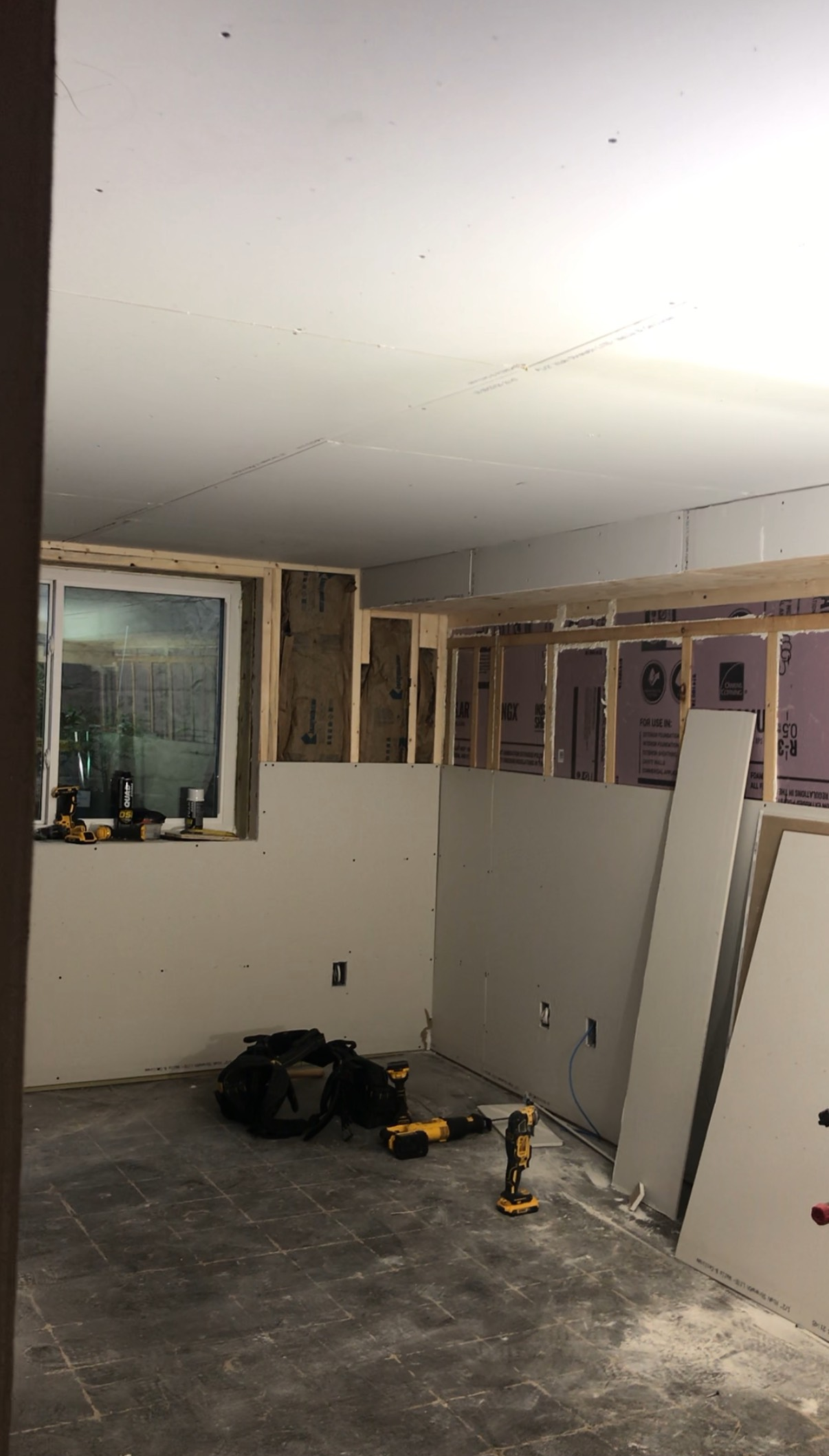 A room with a window and a drill in it is being remodeled.