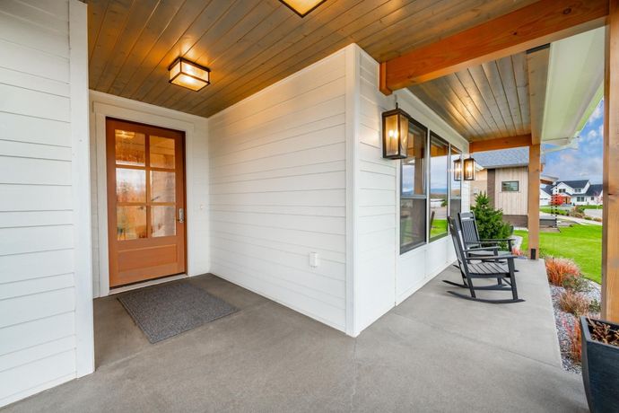 There are rocking chairs on the porch of a house.