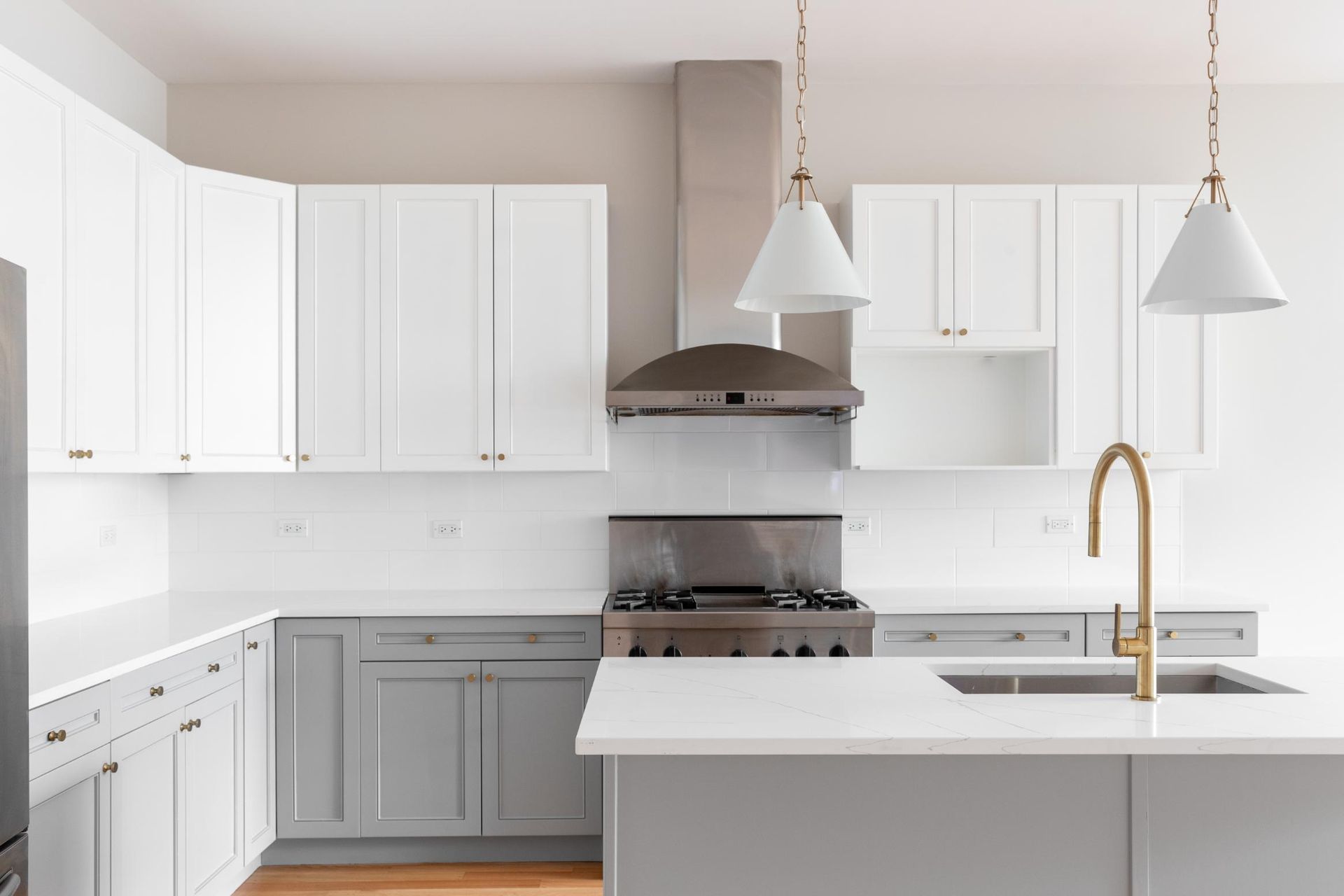 A kitchen with white cabinets , a stove , a sink , and a hood.