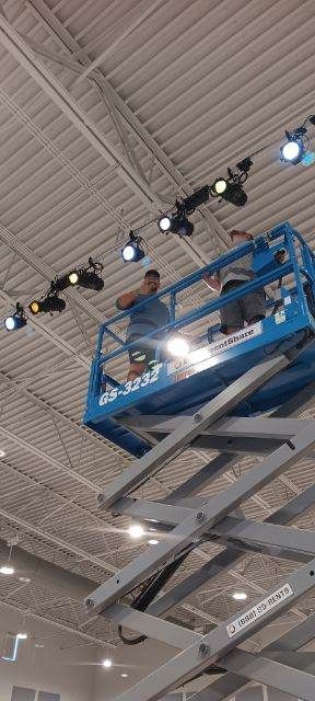 A man is sitting on a scissor lift working on a ceiling.