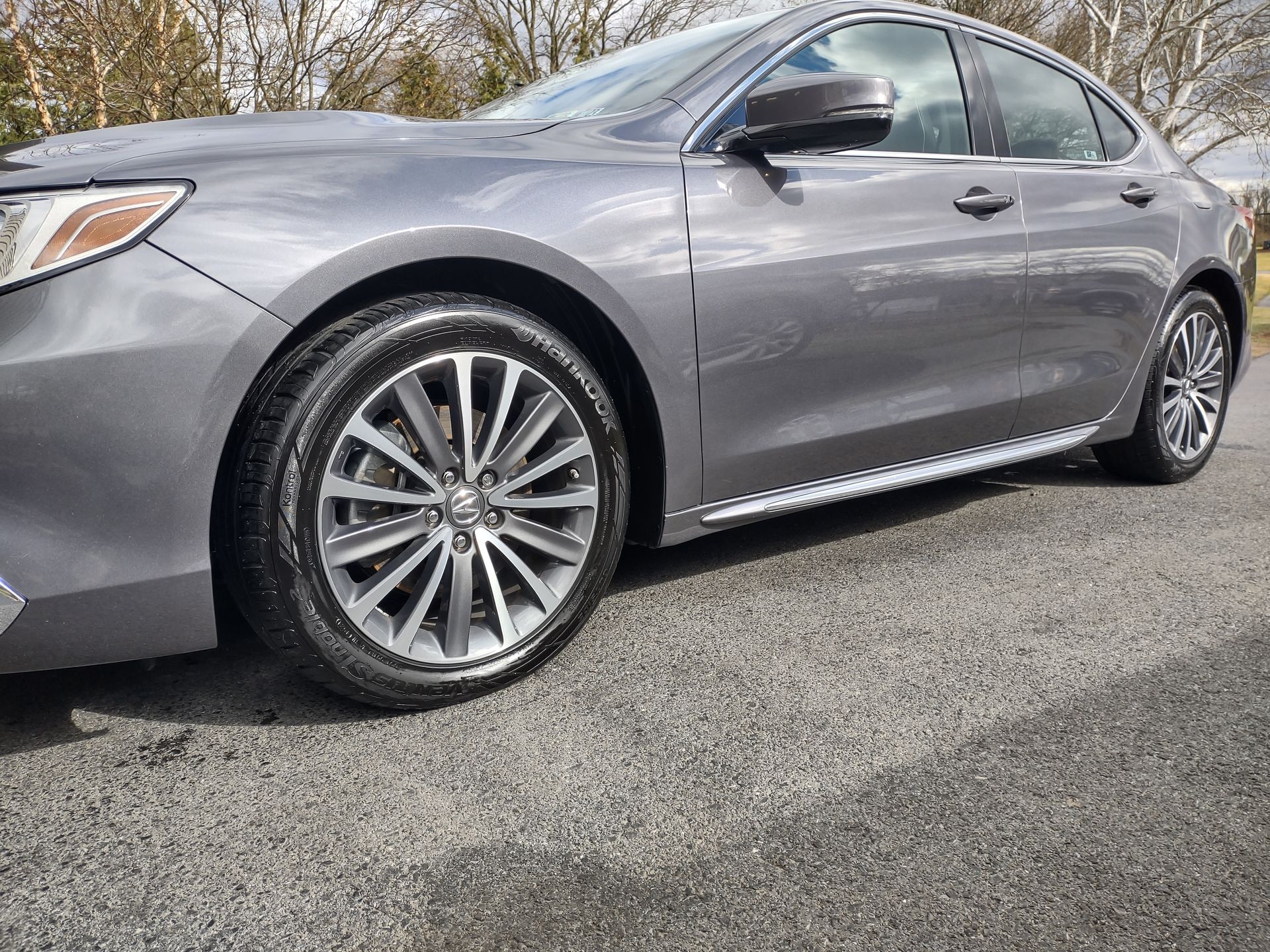 A gray car is parked on the side of the road.