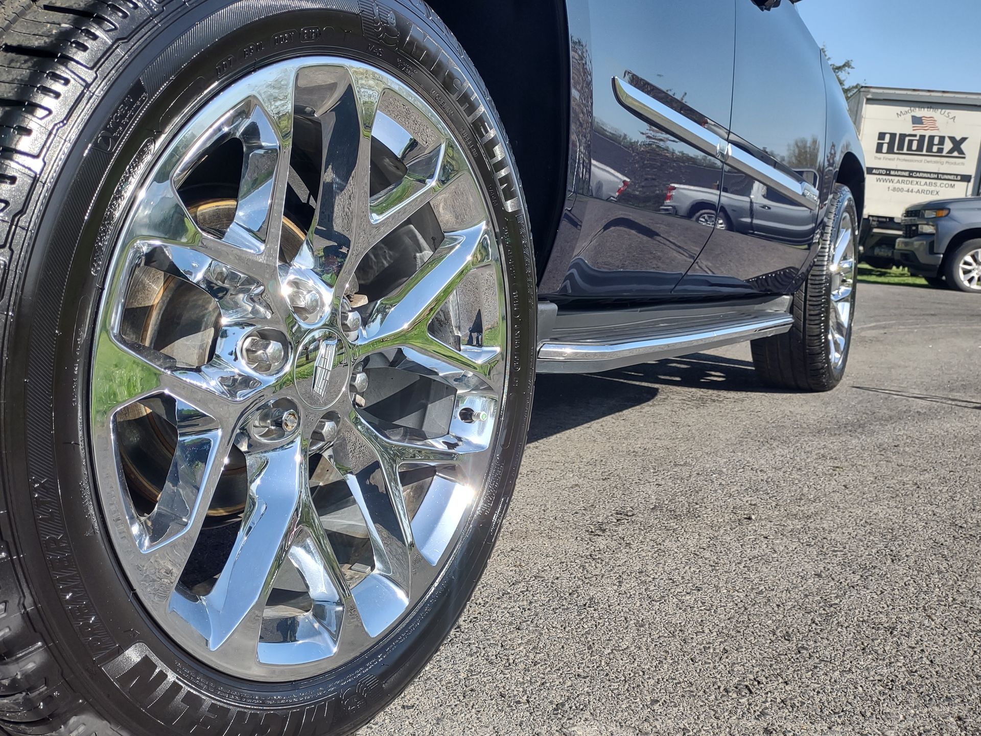 Shiny chrome wheel and tire on a dark SUV parked on pavement.