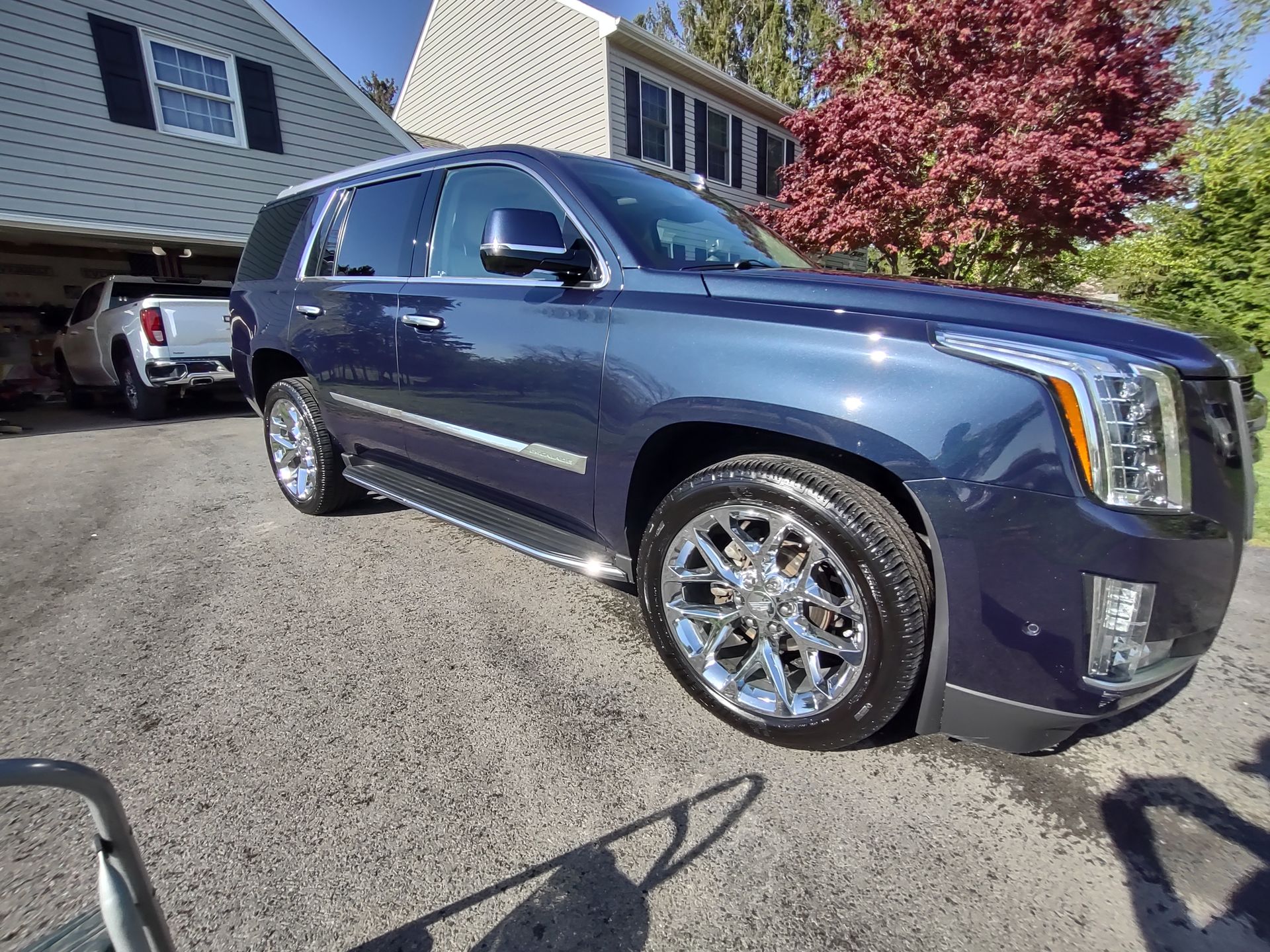A blue suv is parked in a driveway in front of a house.