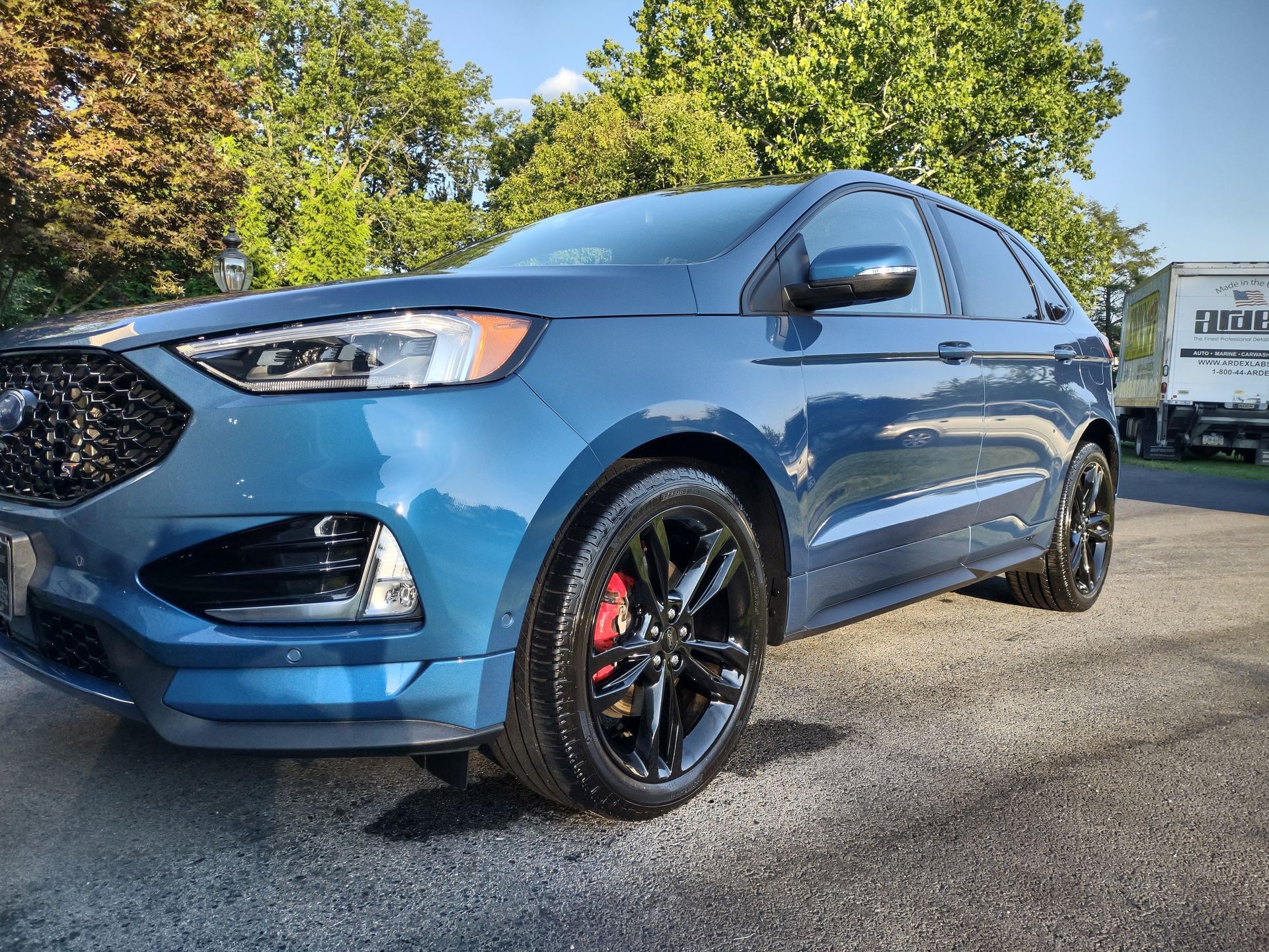 A blue ford edge is parked on the side of the road.