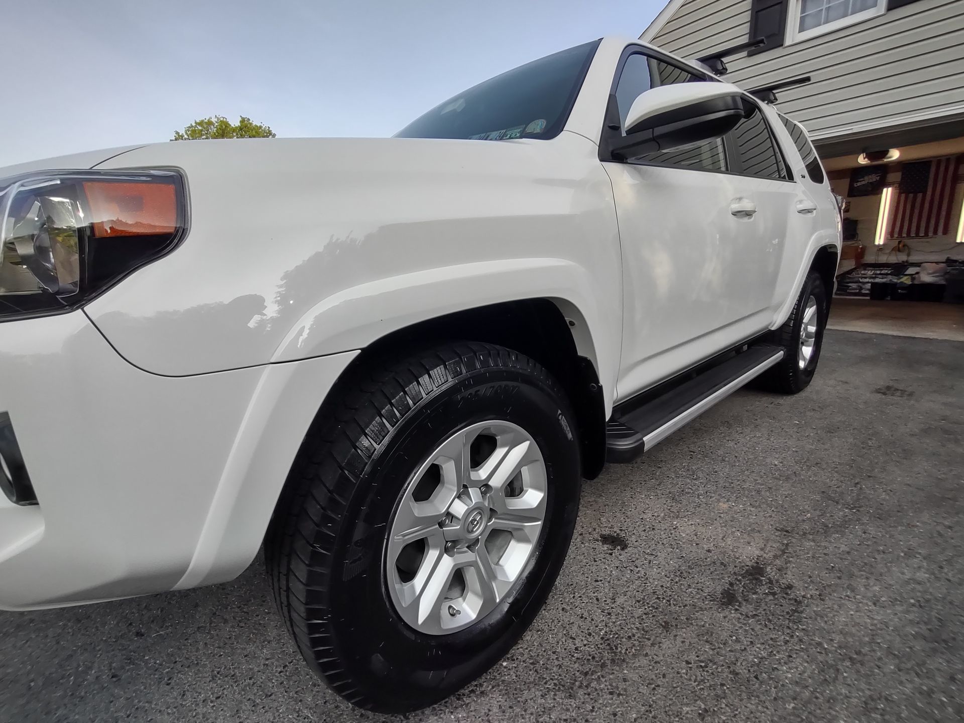 A white toyota 4runner is parked in front of a house.