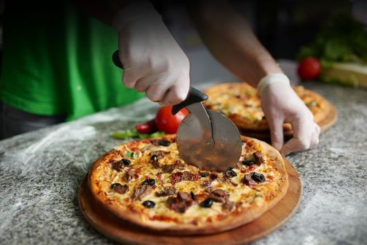 person cutting pizza