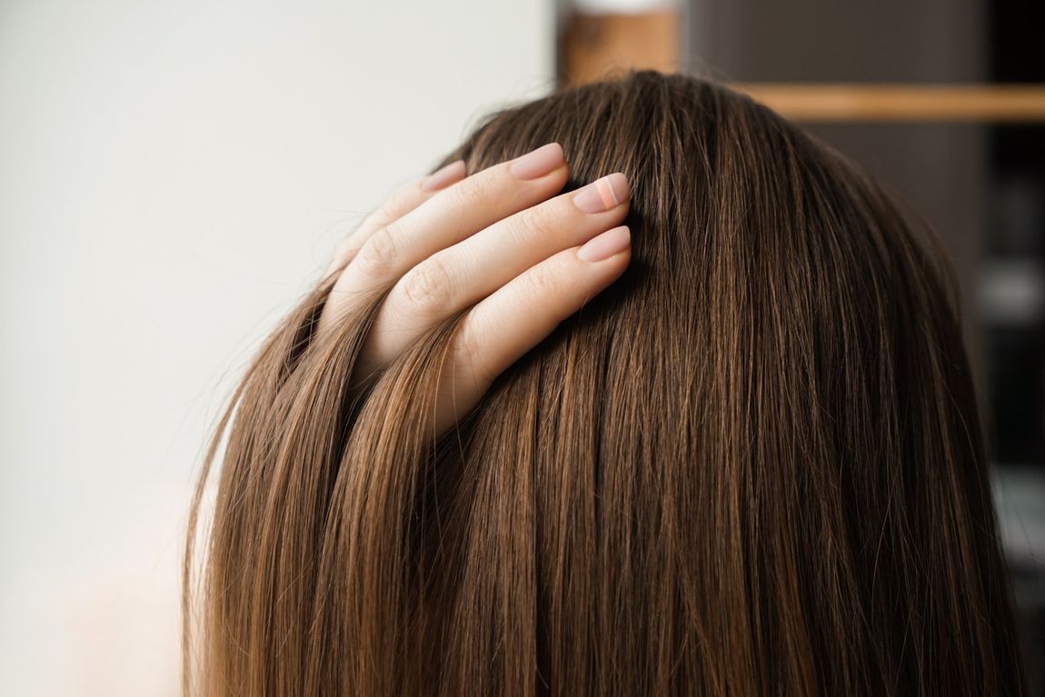 Finger fahren durch glänzendes, dunkles Haar