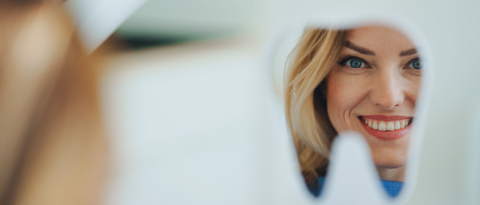 Una donna sorride in uno specchio a forma di dente.