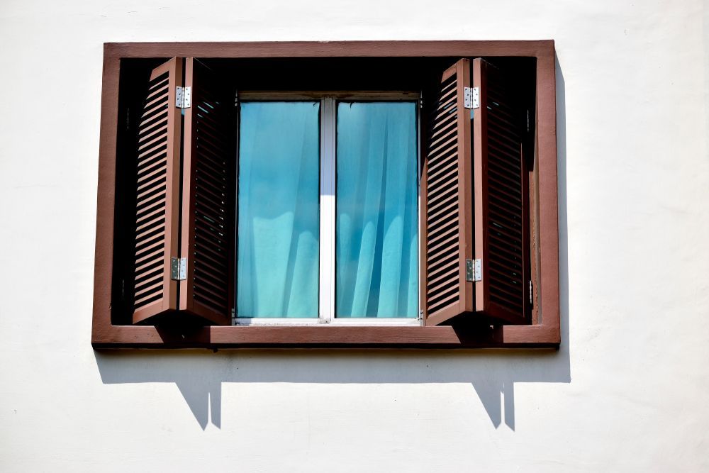 A Window With Shutters Open On A White Wall — Roo’s Door & Window Maintenance In Maroochydore, QLD