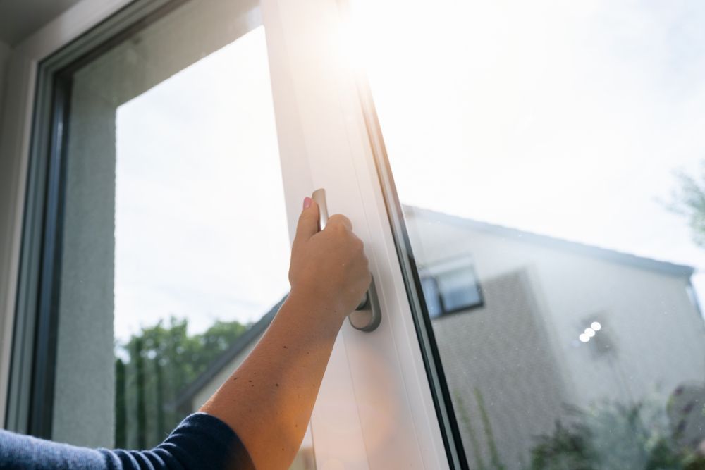 A Person Is Opening A Window With The Sun Shining Through It — Roo’s Door & Window Maintenance In Nambour, QLD