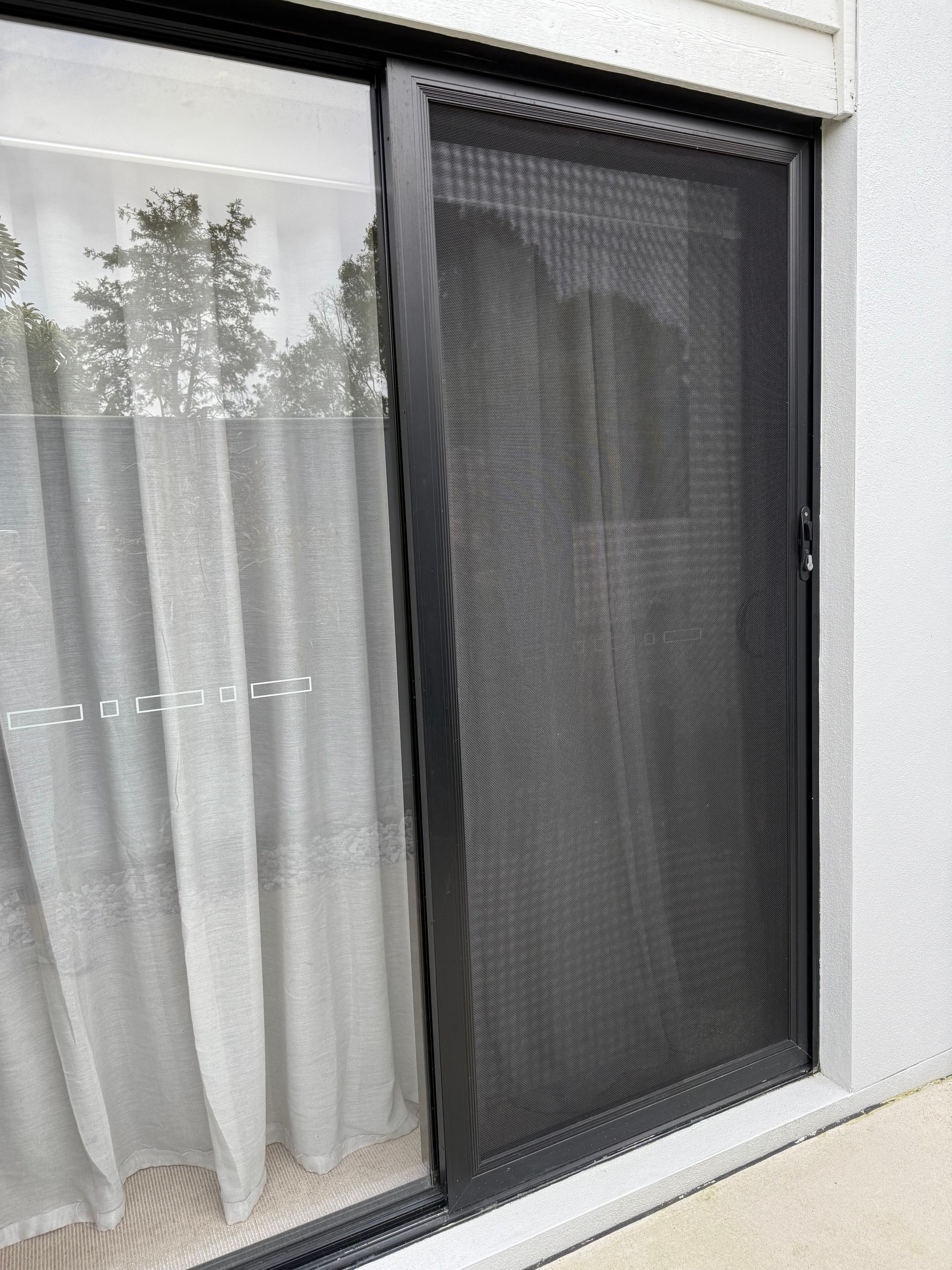 A Close Up Of A Screen Door With A View Of A Garden Through It — Roo’s Door & Window Maintenance In Sippy Downs, QLD
