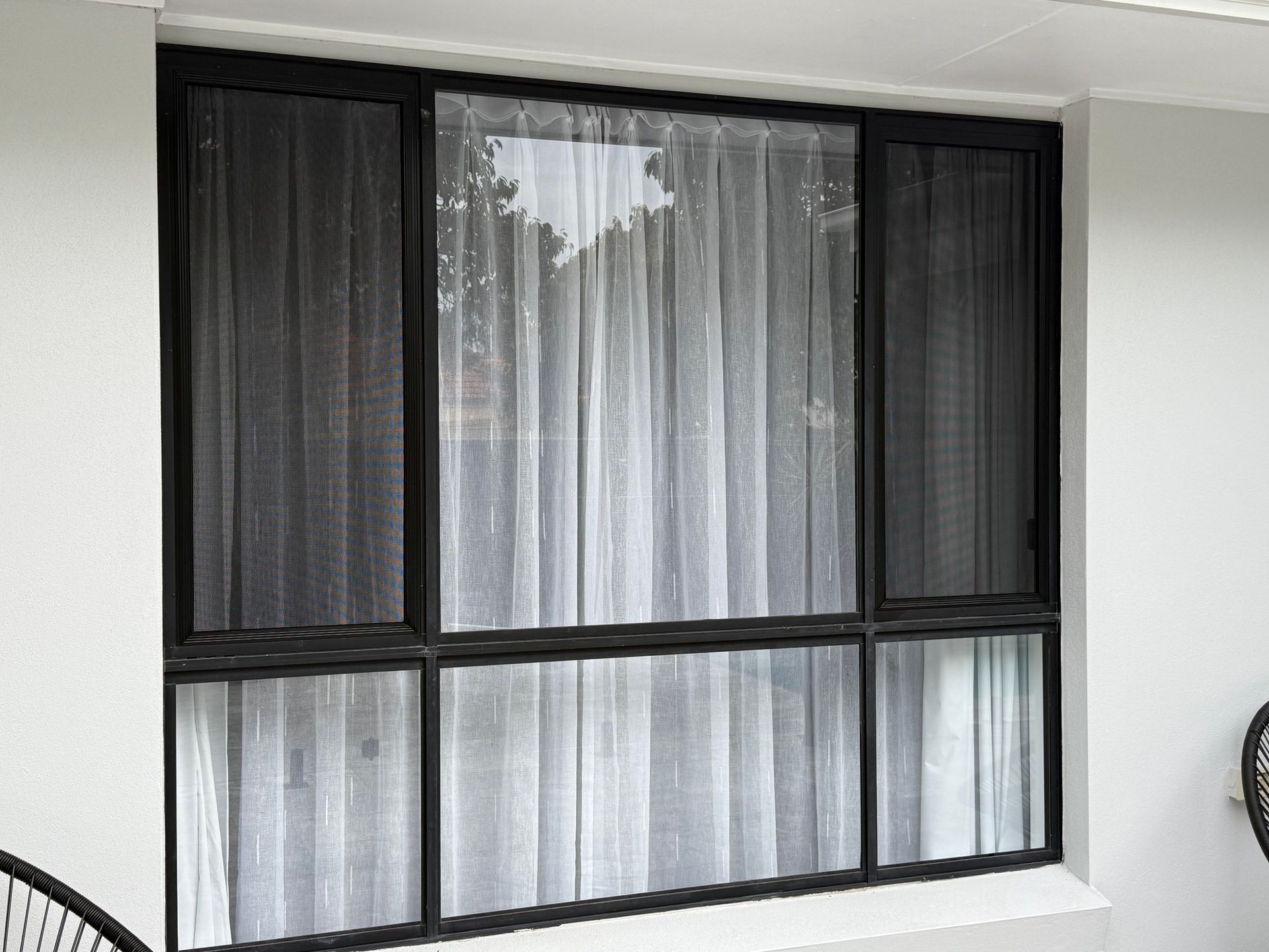 A Person Is Opening A Screen Door With A Black Handle — Roo’s Door & Window Maintenance In Sippy Downs, QLD